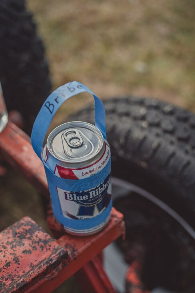 An unopened beer can sitting on a car frame